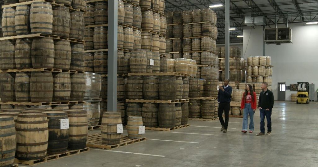 Rows of authentic used bourbon barrels stacked in climate-controlled warehouse showing sustainable aging solution storage